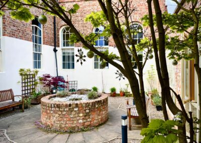 Courtyard area with potted plants, ramp, trees and seating