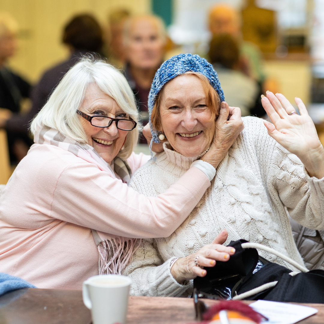 Image of two older white women laughing and waving to the camera